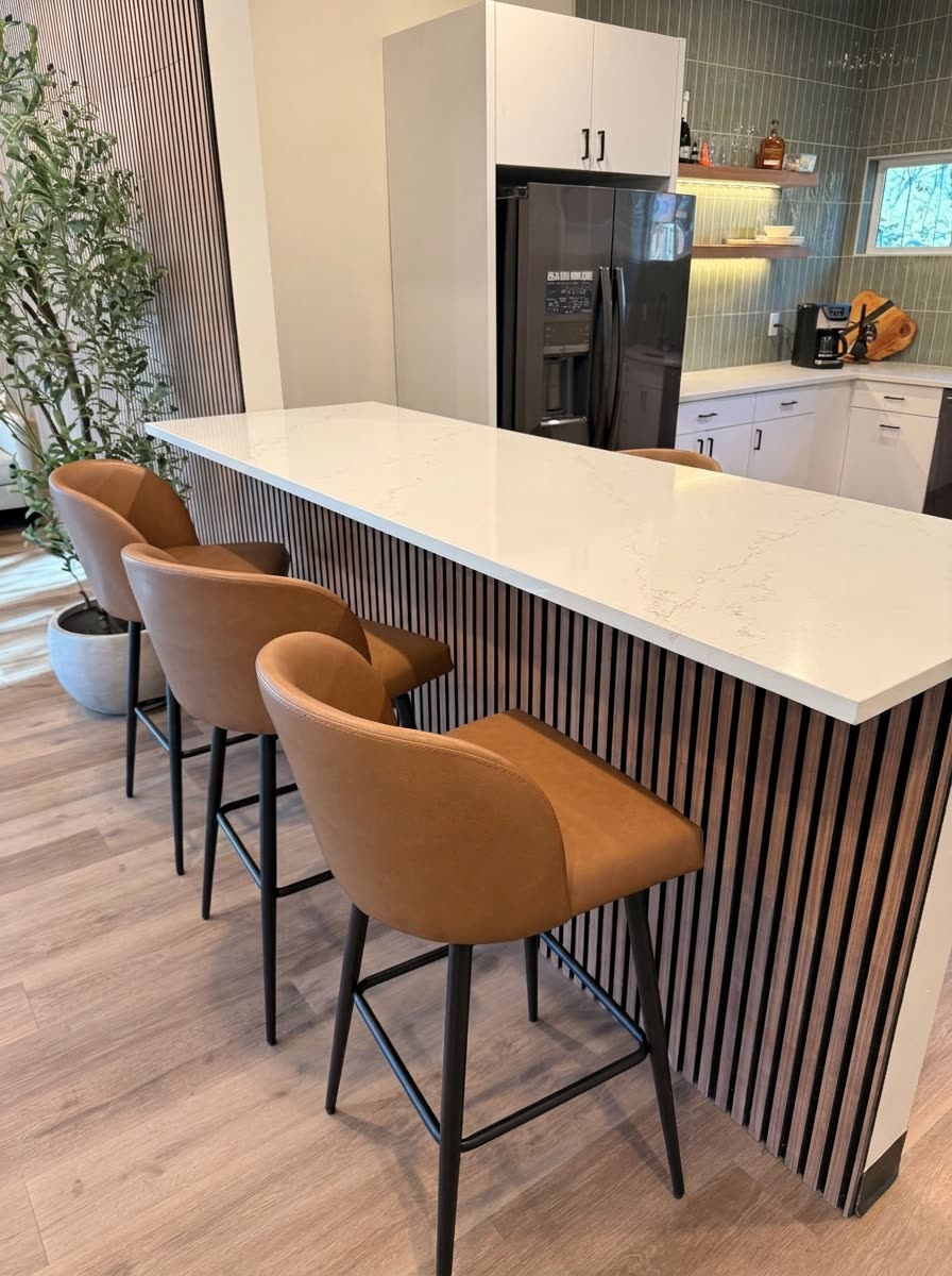 Rubicon Construction break room island with black slatted base, white quartz waterfall counter and cognac leather barstools.