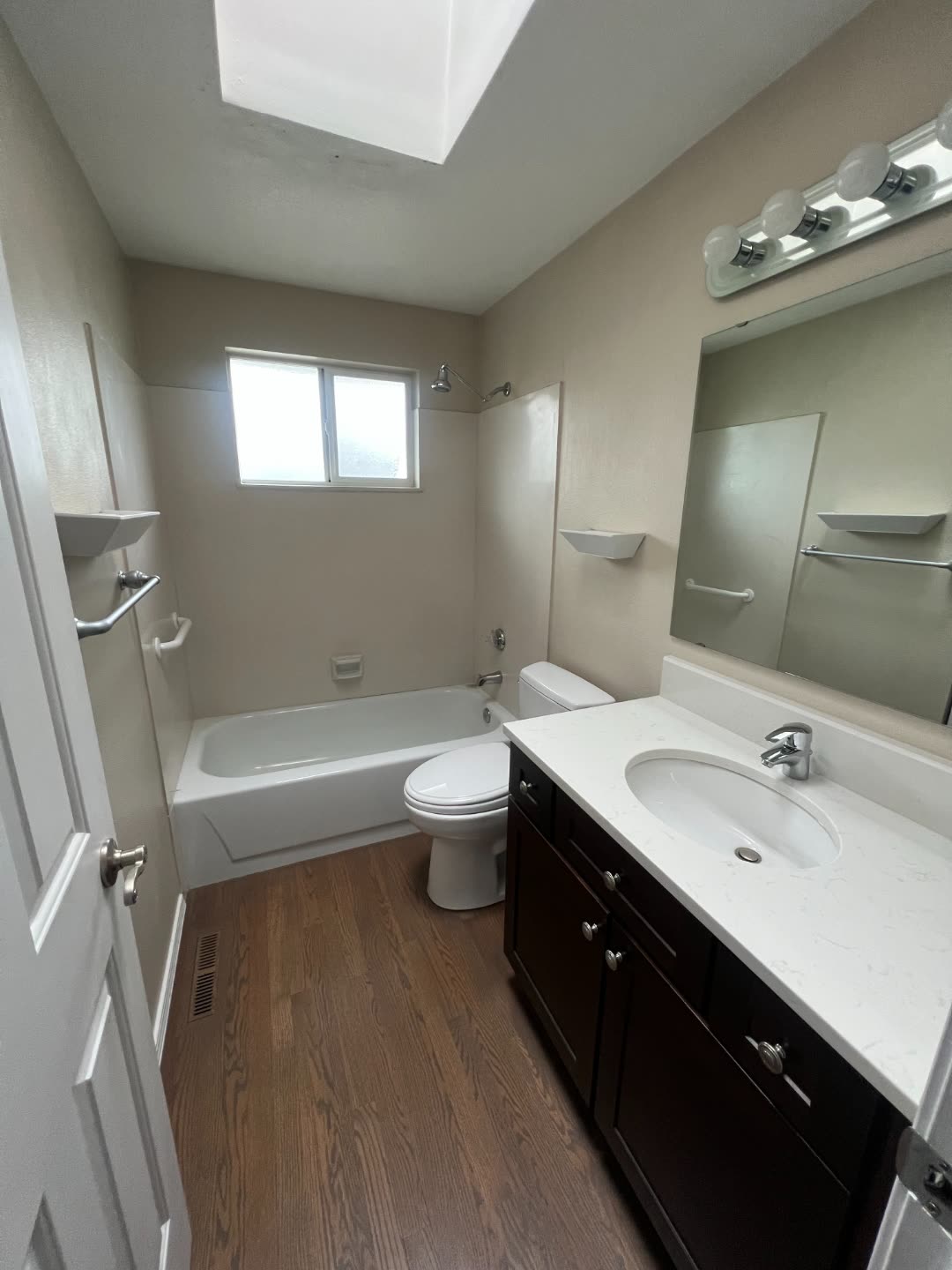 Winn primary bath before remodel — beige walls, builder-grade tub/shower combo and basic globe vanity light.